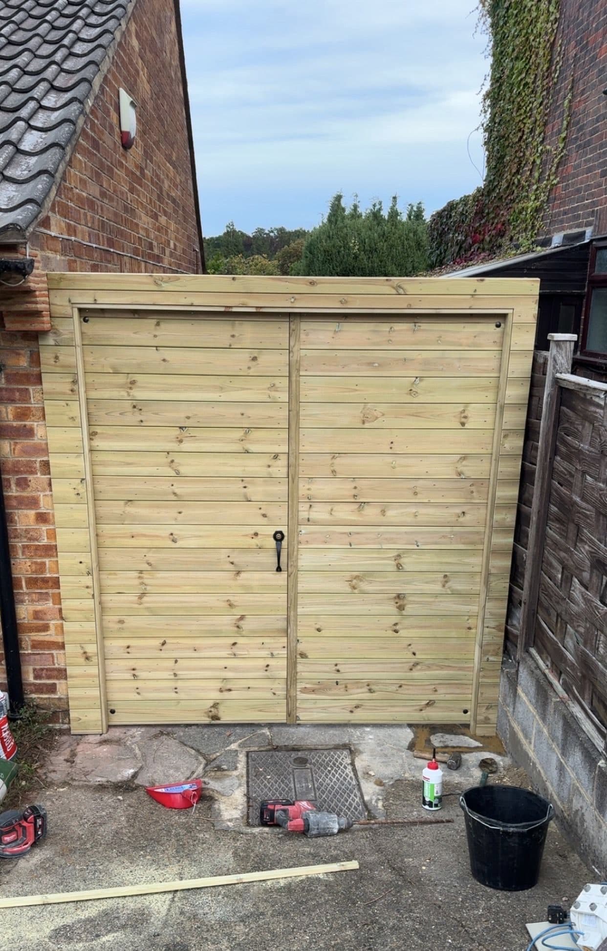 Close-boarded timber side gates fitted across a side return, seen from the street with nothing to climb