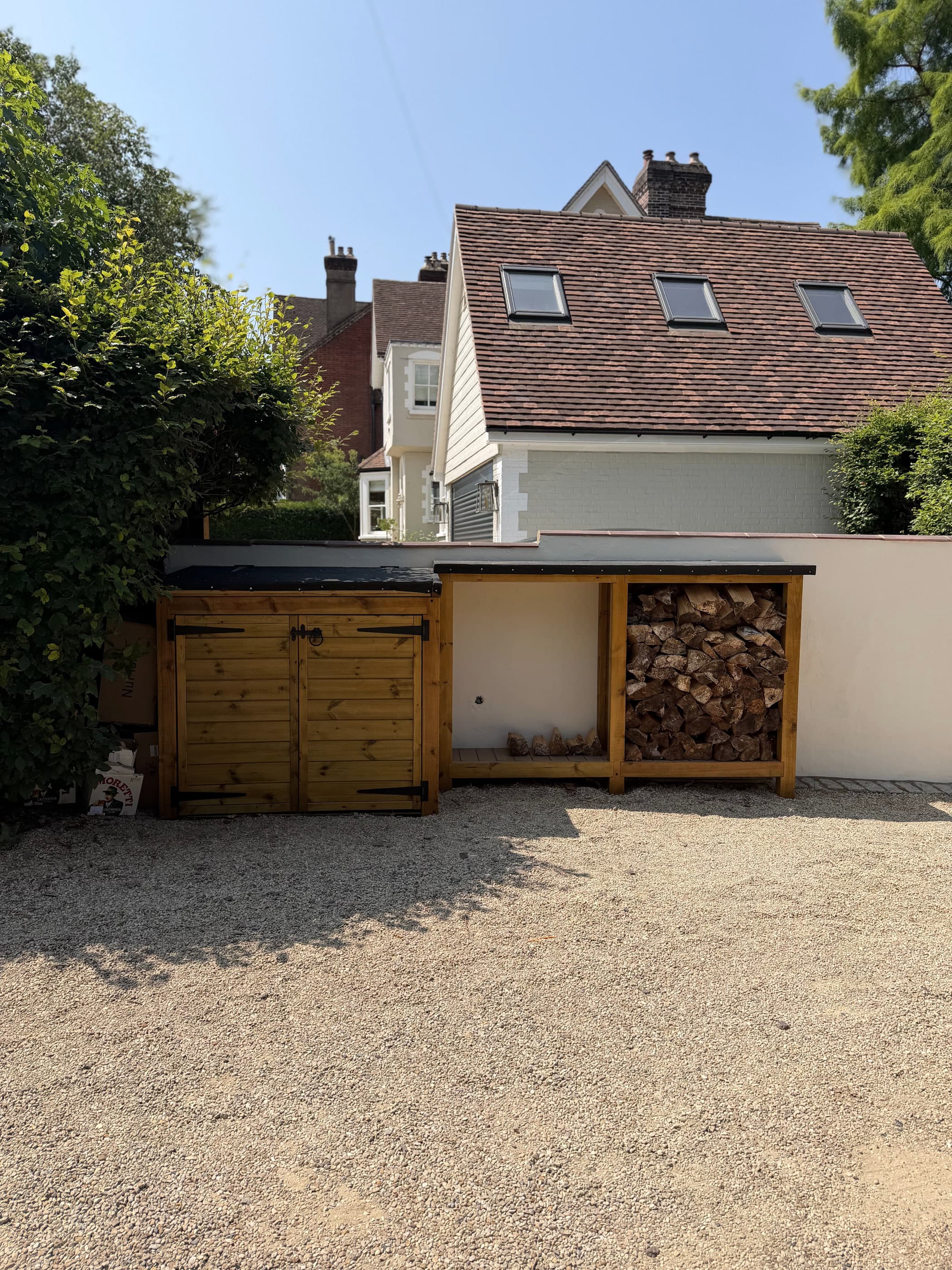 Bespoke timber bin store and log store built along a driveway wall of a Surrey house