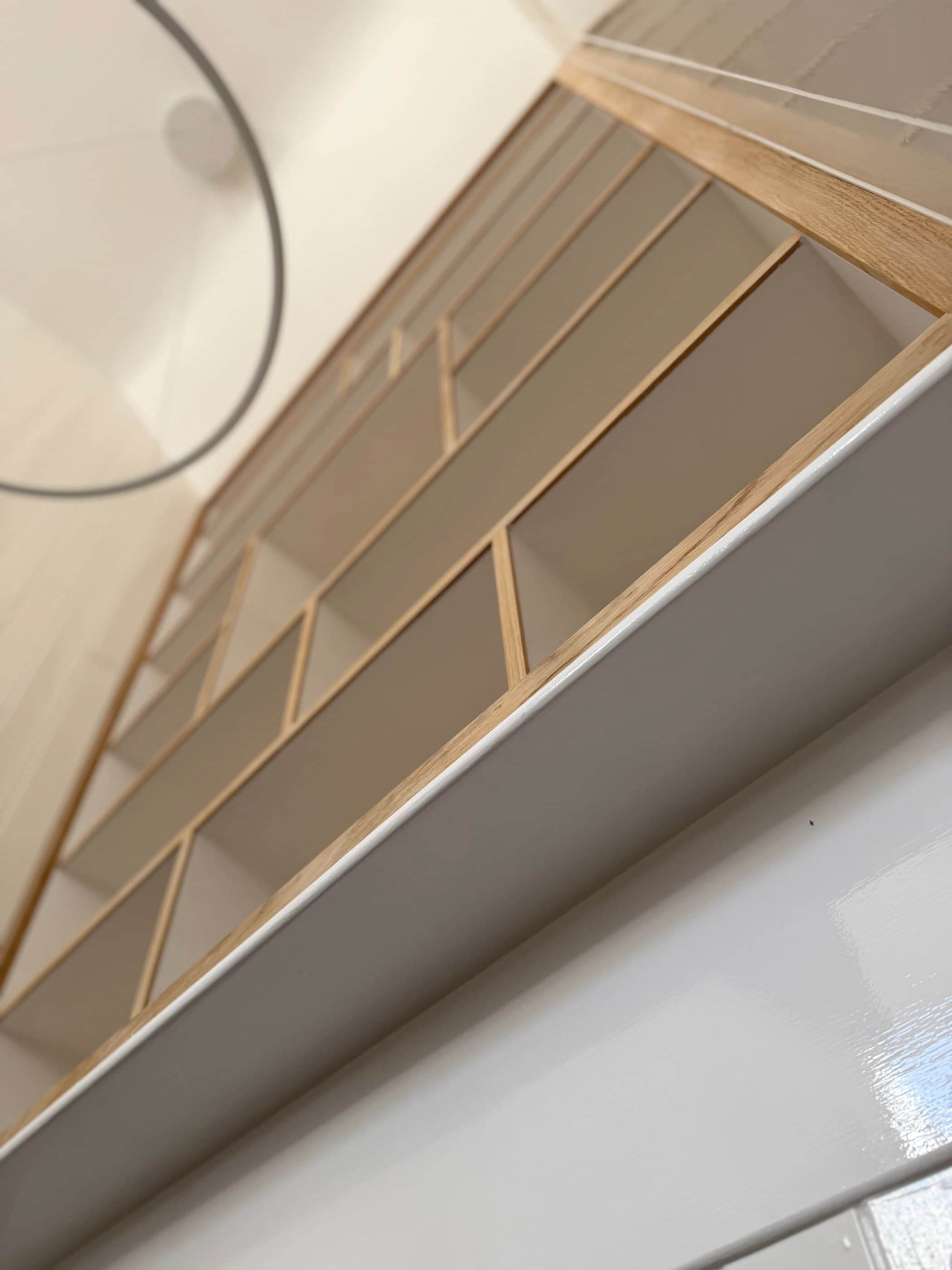 The edge of a bespoke oak shelving unit built by RGS Carpentry, meeting a painted stairwell wall